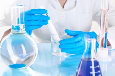 Photo of Scientist examining water with nitrate tester at white table in laboratory, closeup