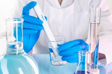 Photo of Scientist examining water with nitrate tester at white table in laboratory, closeup