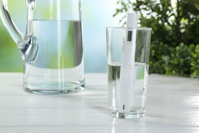 Photo of Nitrate tester in glass of water on white wooden table, closeup