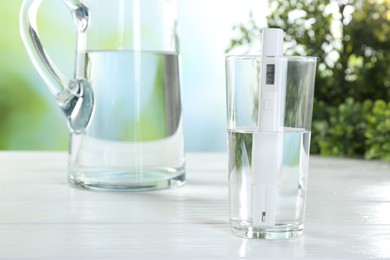 Photo of Nitrate tester in glass of water on white wooden table, closeup