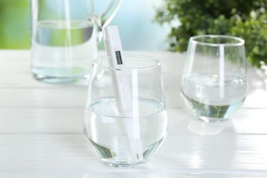 Photo of Nitrate tester in glass of water on white wooden table, closeup