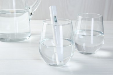 Photo of Nitrate tester in glass of water on white wooden table, closeup