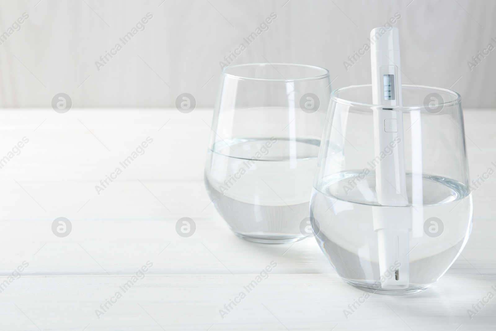 Nitrate tester in glass of water on white wooden table, closeup. Space for text Photo of Nitrate tester in glass of water on white wooden table, closeup. Space for text