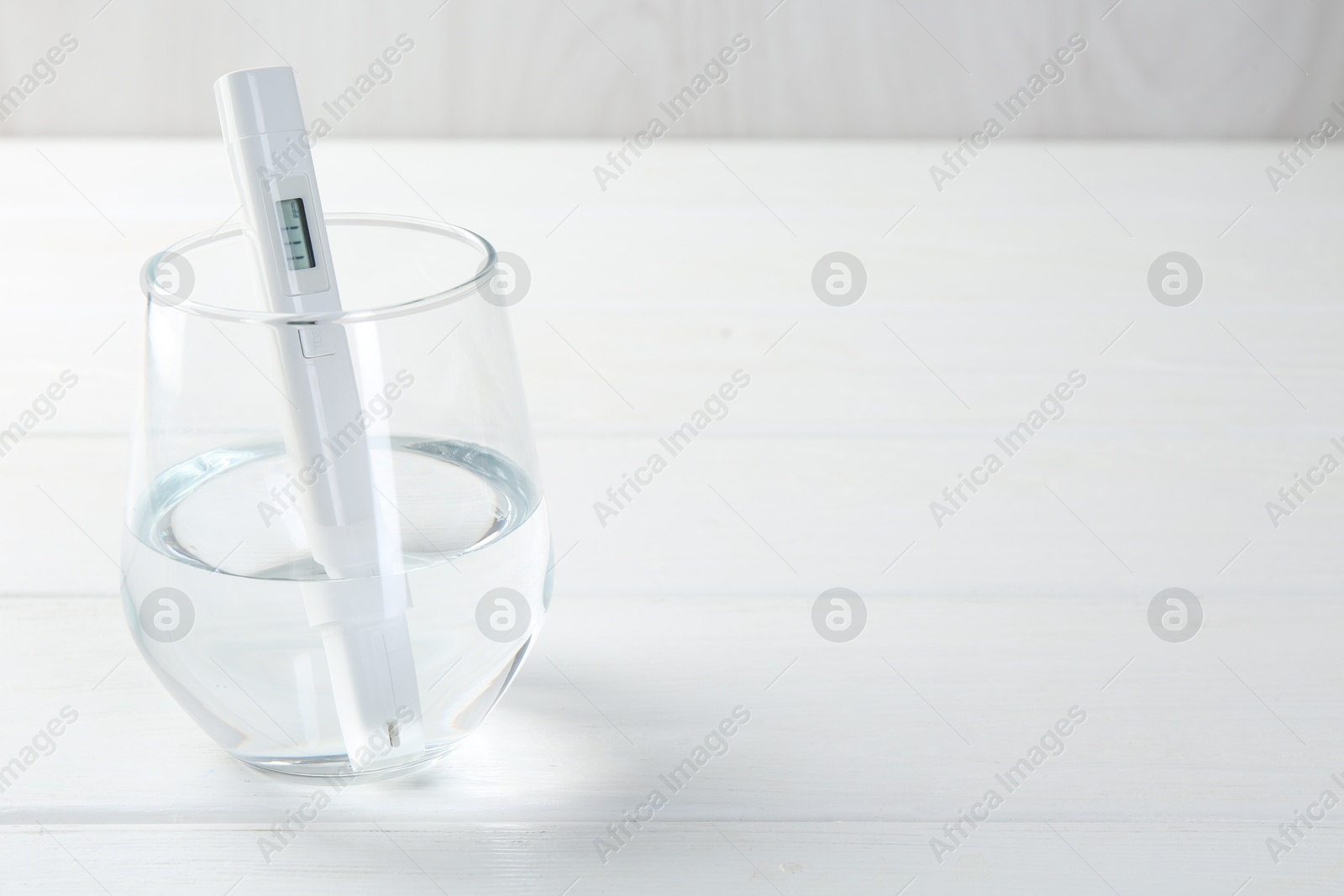 Nitrate tester in glass of water on white wooden table, closeup. Space for text Photo of Nitrate tester in glass of water on white wooden table, closeup. Space for text