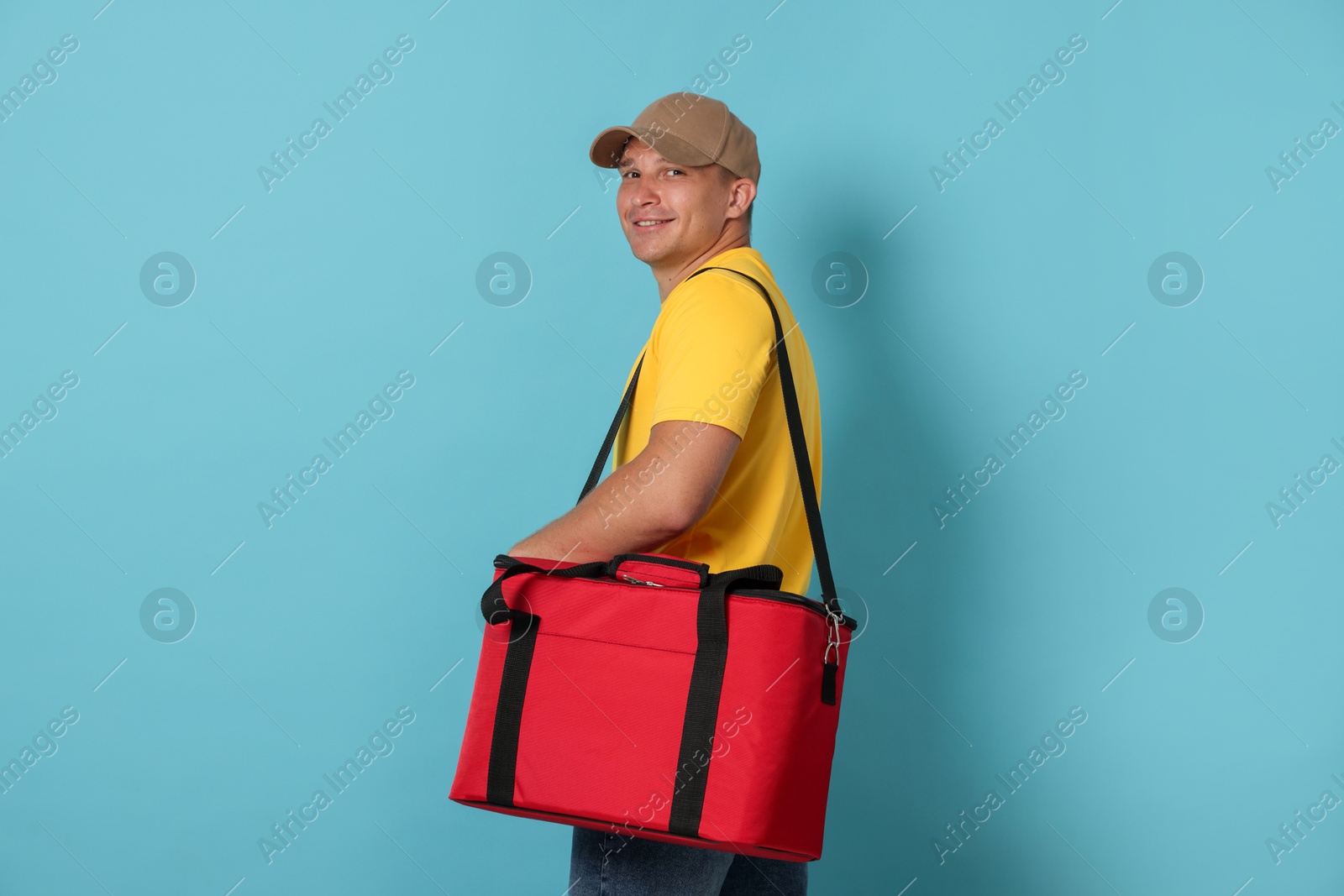Courier with thermo bag on light blue background. Food delivery service Photo of Courier with thermo bag on light blue background. Food delivery service