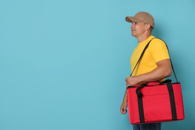 Photo of Courier with thermo bag on light blue background, space for text. Food delivery service