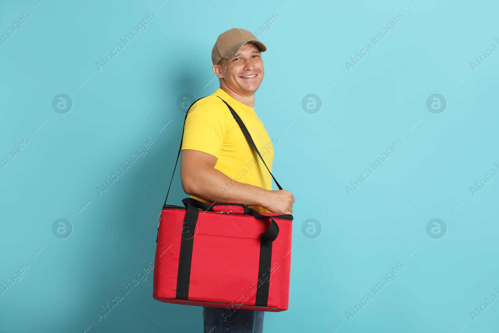 Courier with thermo bag on light blue background. Food delivery service Photo of Courier with thermo bag on light blue background. Food delivery service