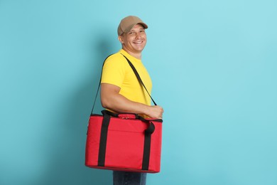 Photo of Courier with thermo bag on light blue background. Food delivery service
