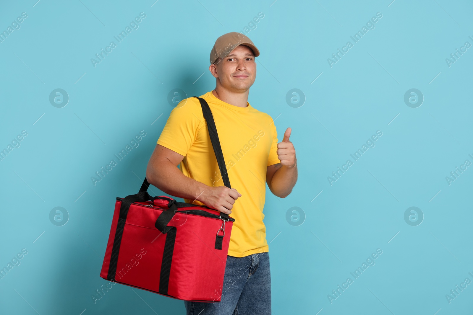 Courier with thermo bag showing thumbs up on light blue background. Food delivery service Photo of Courier with thermo bag showing thumbs up on light blue background. Food delivery service