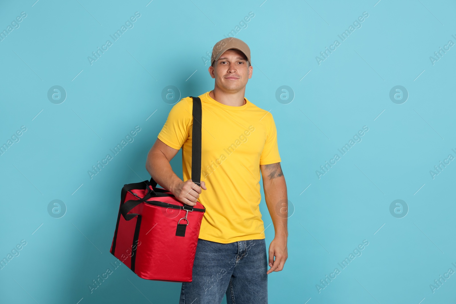 Courier with thermo bag on light blue background. Food delivery service Photo of Courier with thermo bag on light blue background. Food delivery service