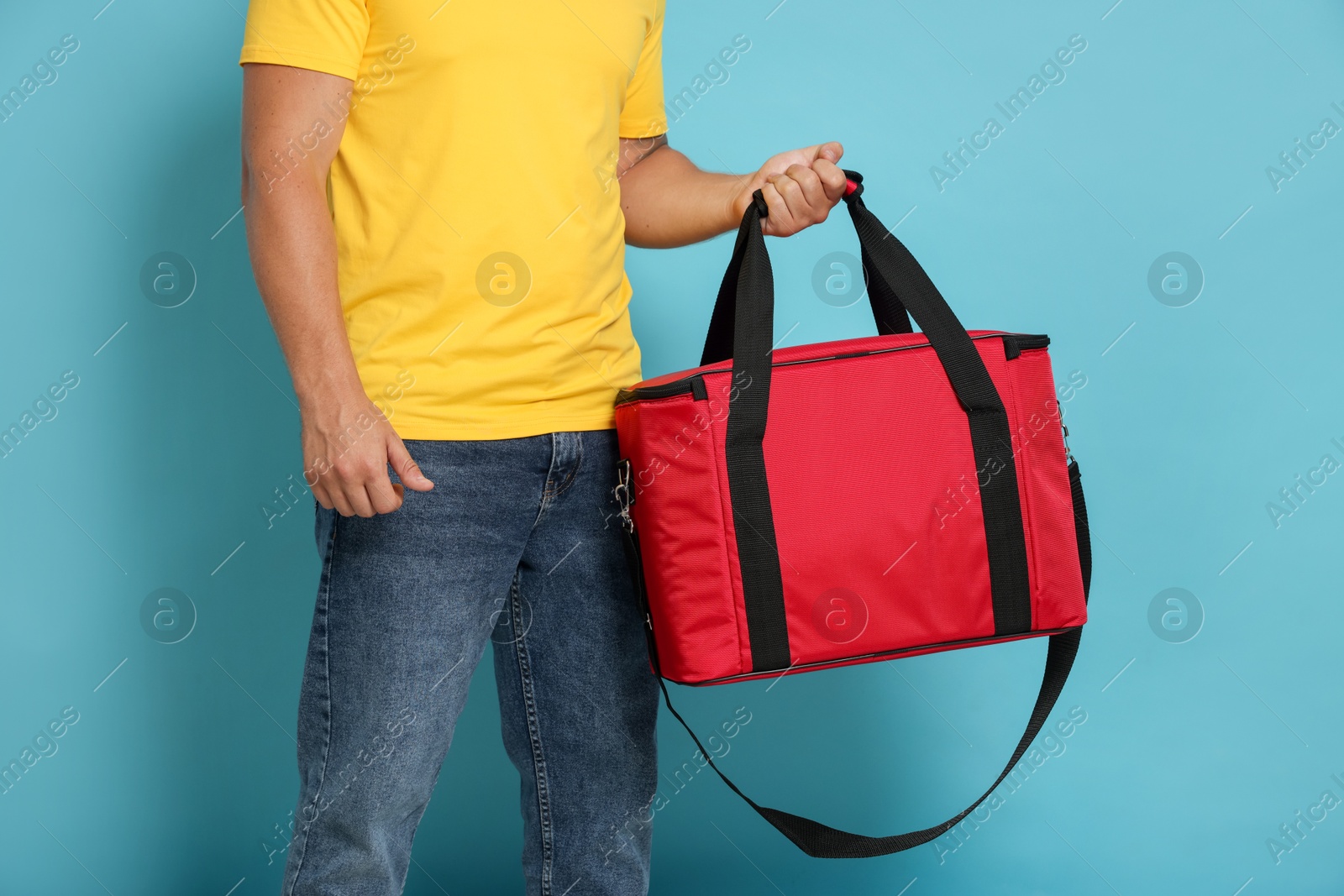 Courier with thermo bag on light blue background, closeup. Food delivery service Photo of Courier with thermo bag on light blue background, closeup. Food delivery service