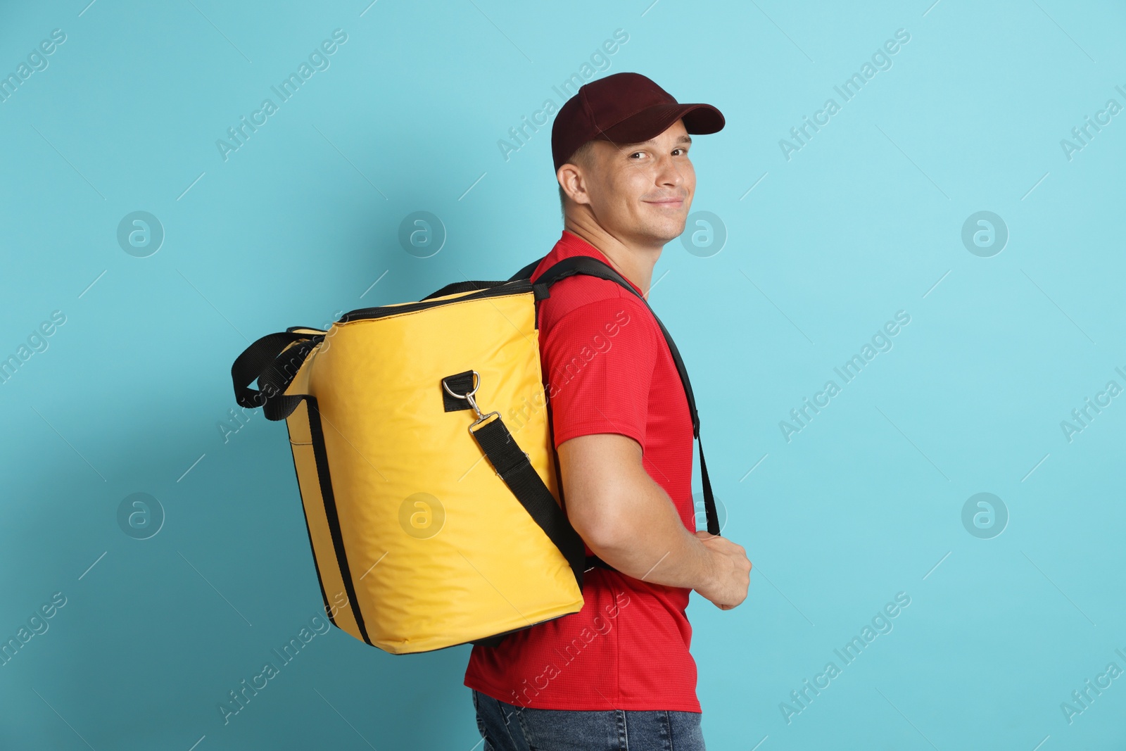 Courier with thermo bag on light blue background. Food delivery service Photo of Courier with thermo bag on light blue background. Food delivery service