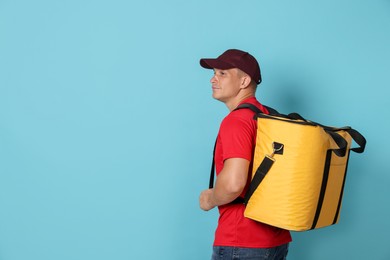 Photo of Courier with thermo bag on light blue background, space for text. Food delivery service