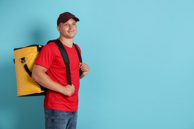 Photo of Courier with thermo bag on light blue background, space for text. Food delivery service