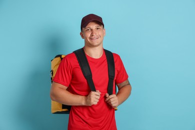 Photo of Courier with thermo bag on light blue background. Food delivery service