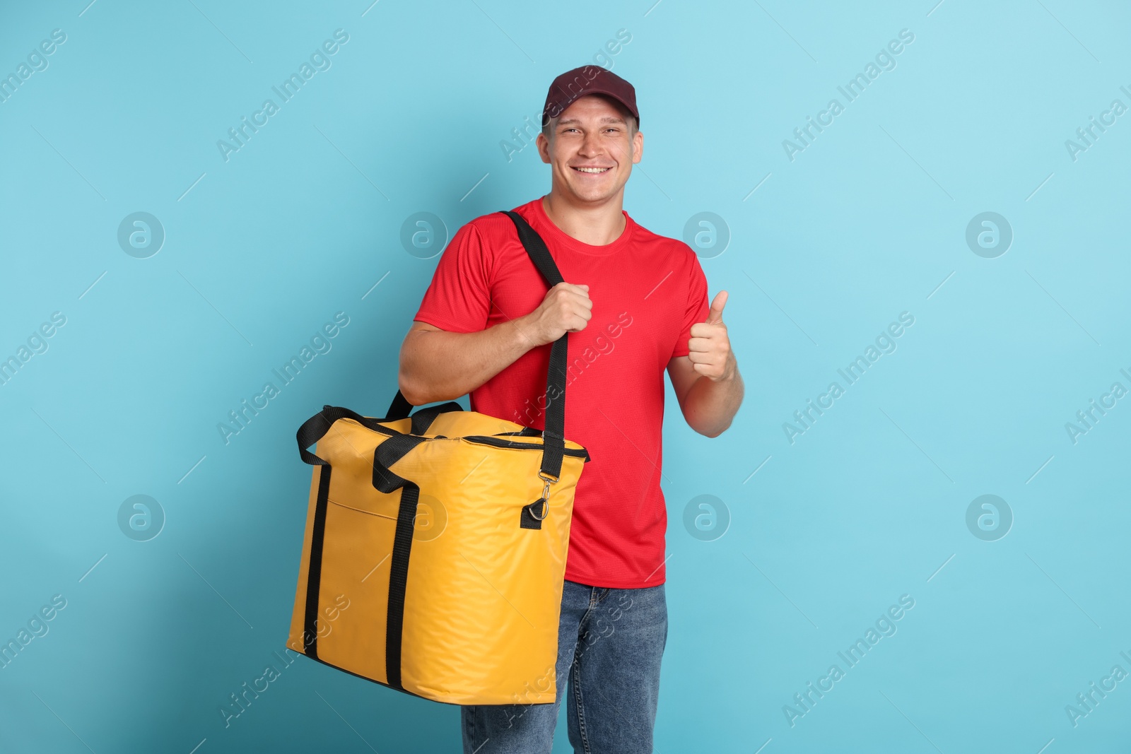 Courier with thermo bag showing thumbs up on light blue background. Food delivery service Photo of Courier with thermo bag showing thumbs up on light blue background. Food delivery service