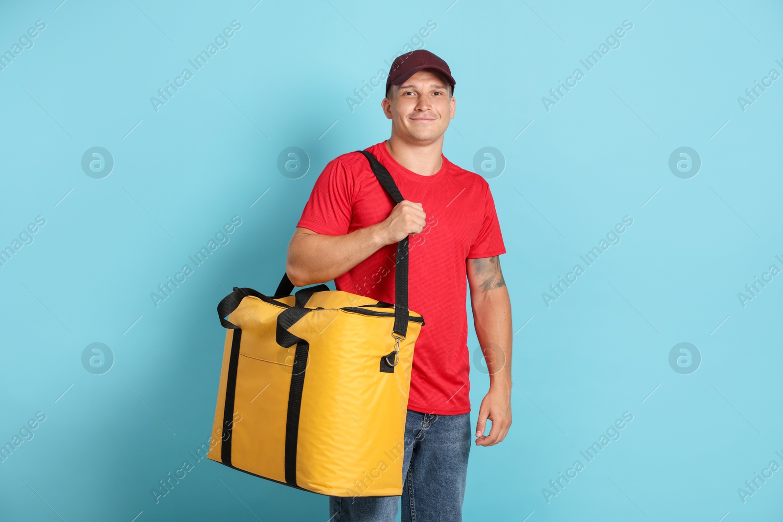 Courier with thermo bag on light blue background. Food delivery service Photo of Courier with thermo bag on light blue background. Food delivery service