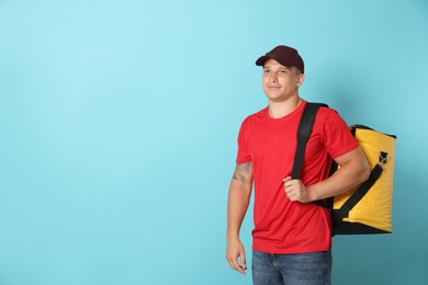 Photo of Courier with thermo bag on light blue background, space for text. Food delivery service