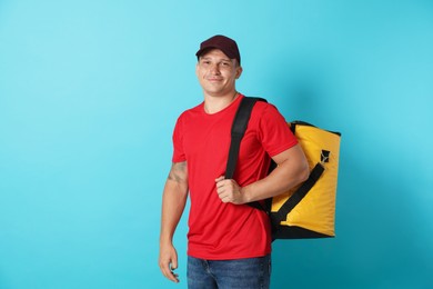 Photo of Courier with thermo bag on light blue background. Food delivery service