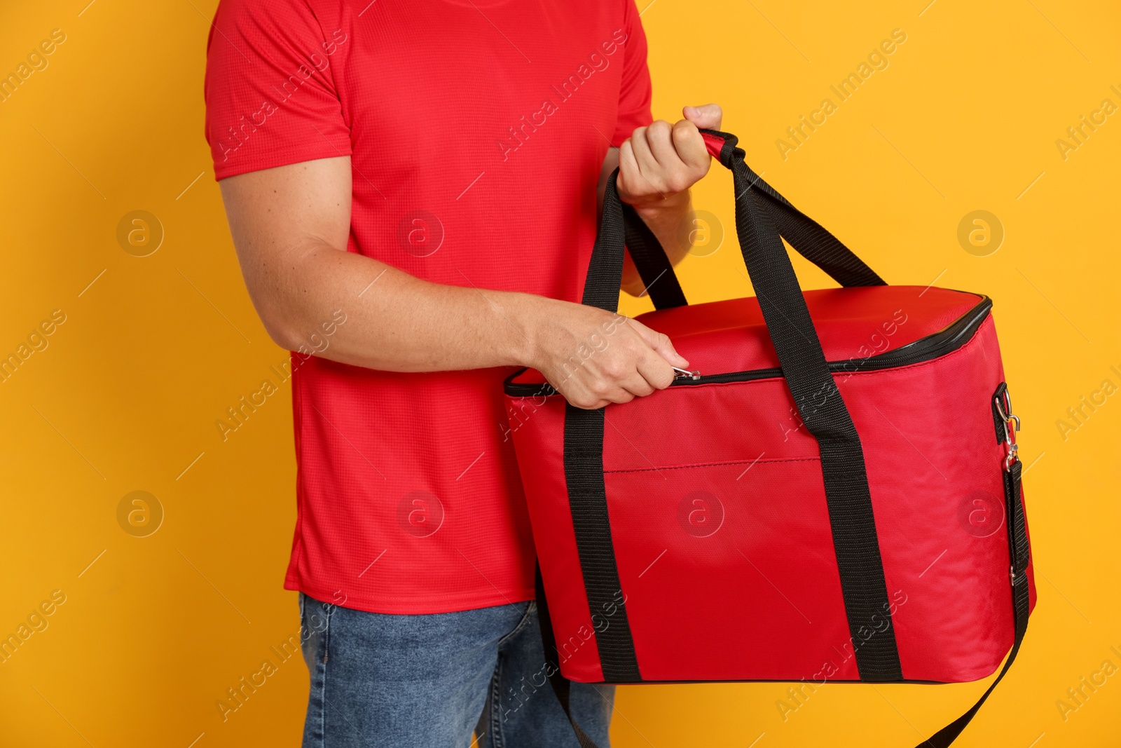 Courier with thermo bag on orange background, closeup. Food delivery service Photo of Courier with thermo bag on orange background, closeup. Food delivery service