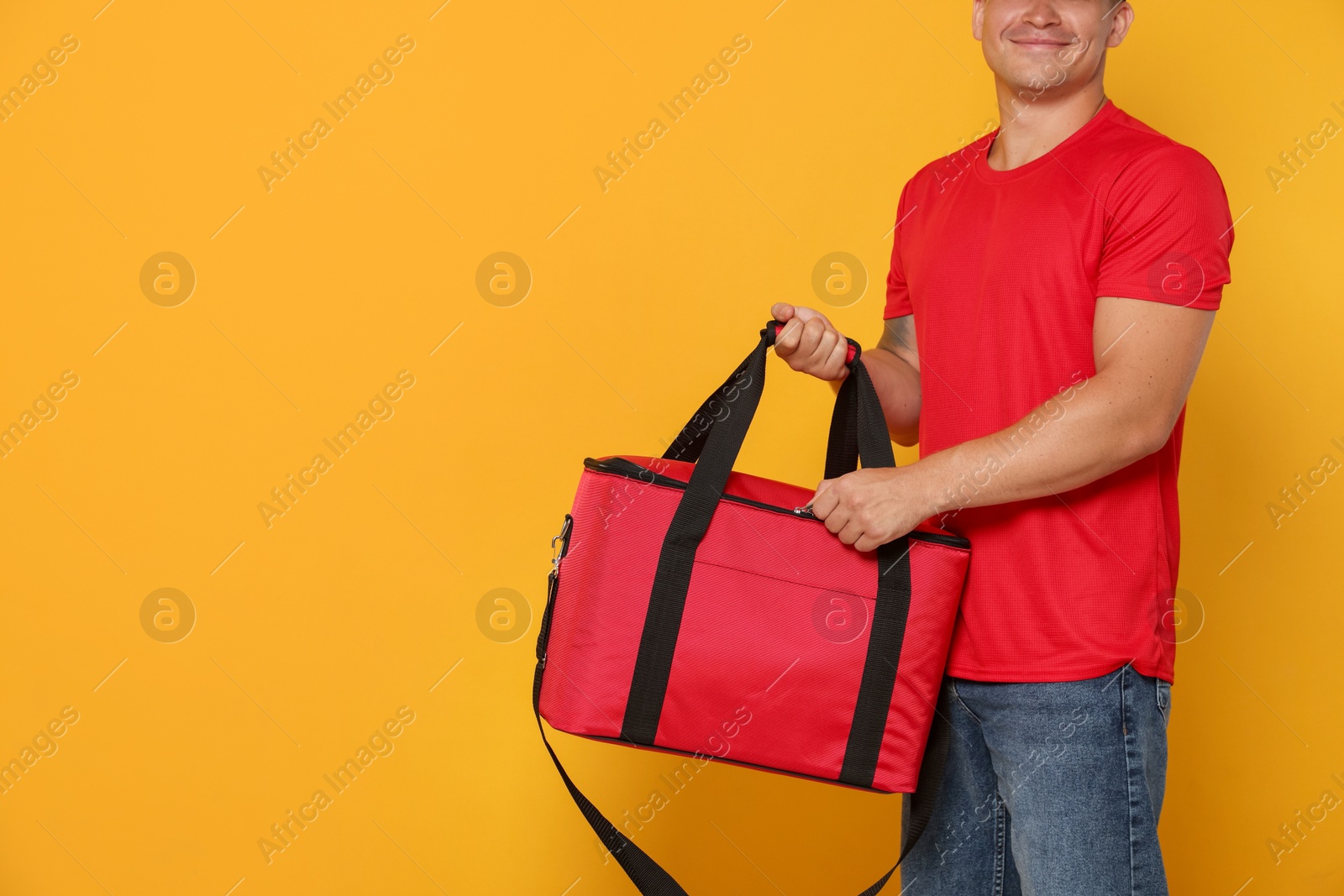 Food delivery service. Courier with thermo bag on orange background, closeup. Space for text Photo of Food delivery service. Courier with thermo bag on orange background, closeup. Space for text
