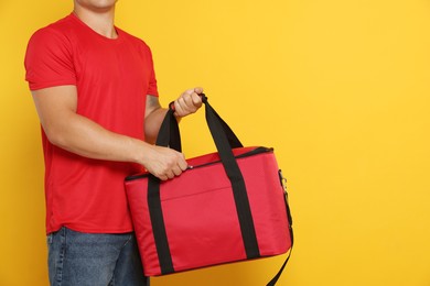 Photo of Food delivery service. Courier with thermo bag on orange background, closeup. Space for text