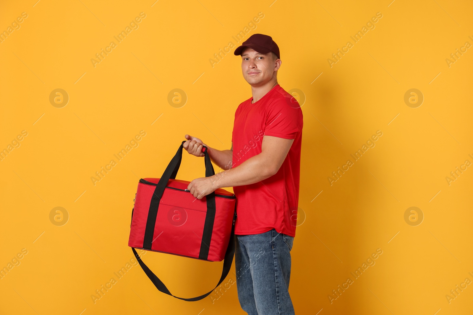 Courier with thermo bag on orange background. Food delivery service Photo of Courier with thermo bag on orange background. Food delivery service