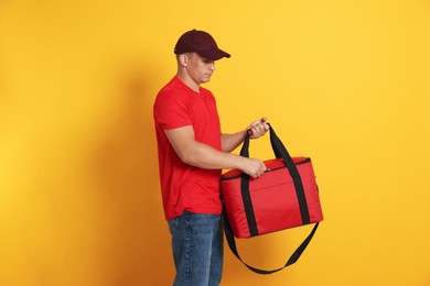 Photo of Courier with thermo bag on orange background. Food delivery service