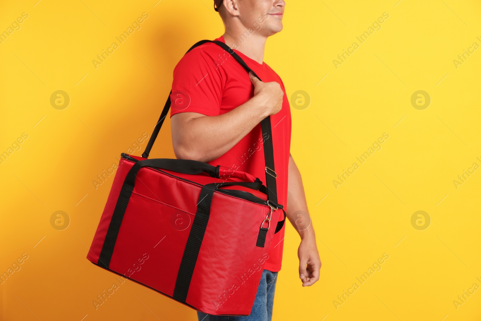 Courier with thermo bag on orange background, closeup. Food delivery service Photo of Courier with thermo bag on orange background, closeup. Food delivery service