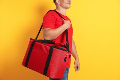 Photo of Courier with thermo bag on orange background, closeup. Food delivery service
