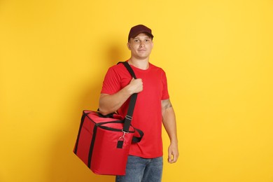 Photo of Courier with thermo bag on orange background. Food delivery service