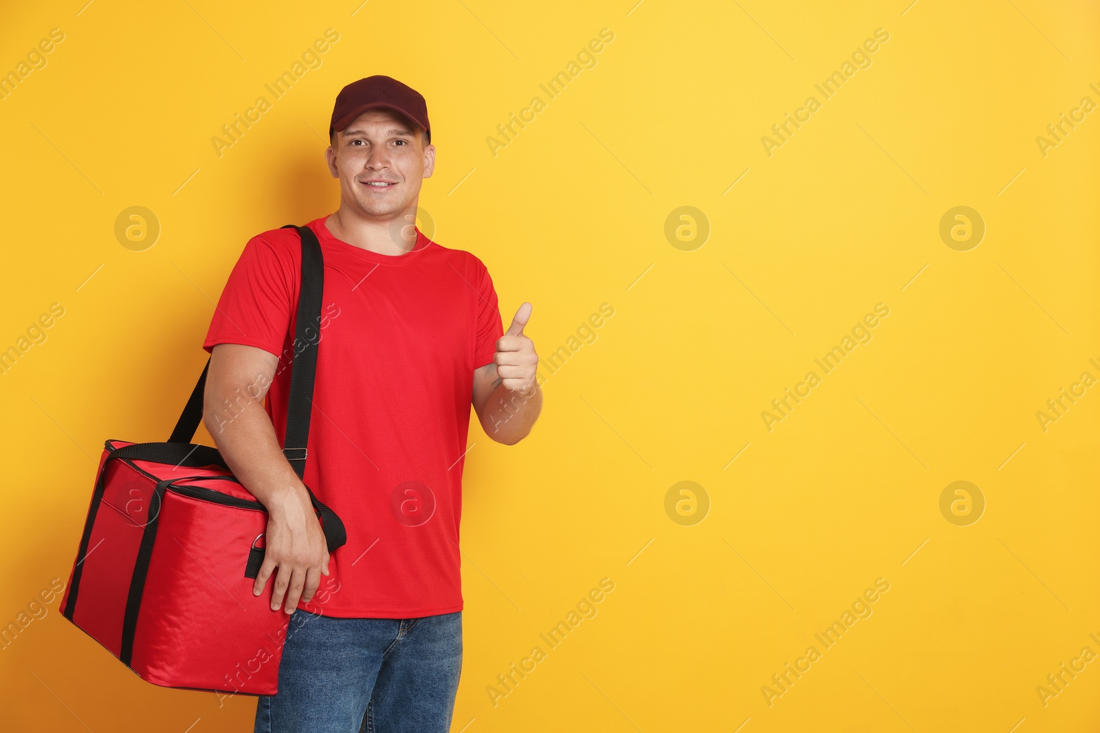 Courier with thermo bag showing thumbs up on orange background, space for text. Food delivery service Photo of Courier with thermo bag showing thumbs up on orange background, space for text. Food delivery service