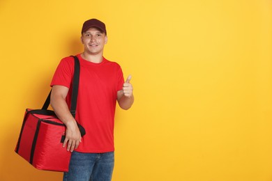 Photo of Courier with thermo bag showing thumbs up on orange background, space for text. Food delivery service