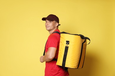 Photo of Courier with thermo bag on yellow background. Food delivery service
