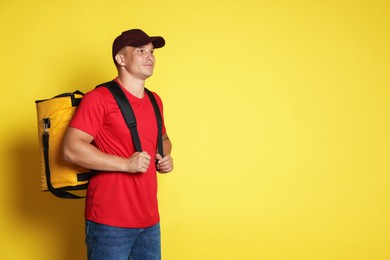 Photo of Courier with thermo bag on yellow background, space for text. Food delivery service