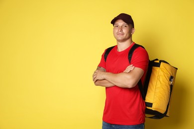 Photo of Courier with thermo bag on yellow background, space for text. Food delivery service