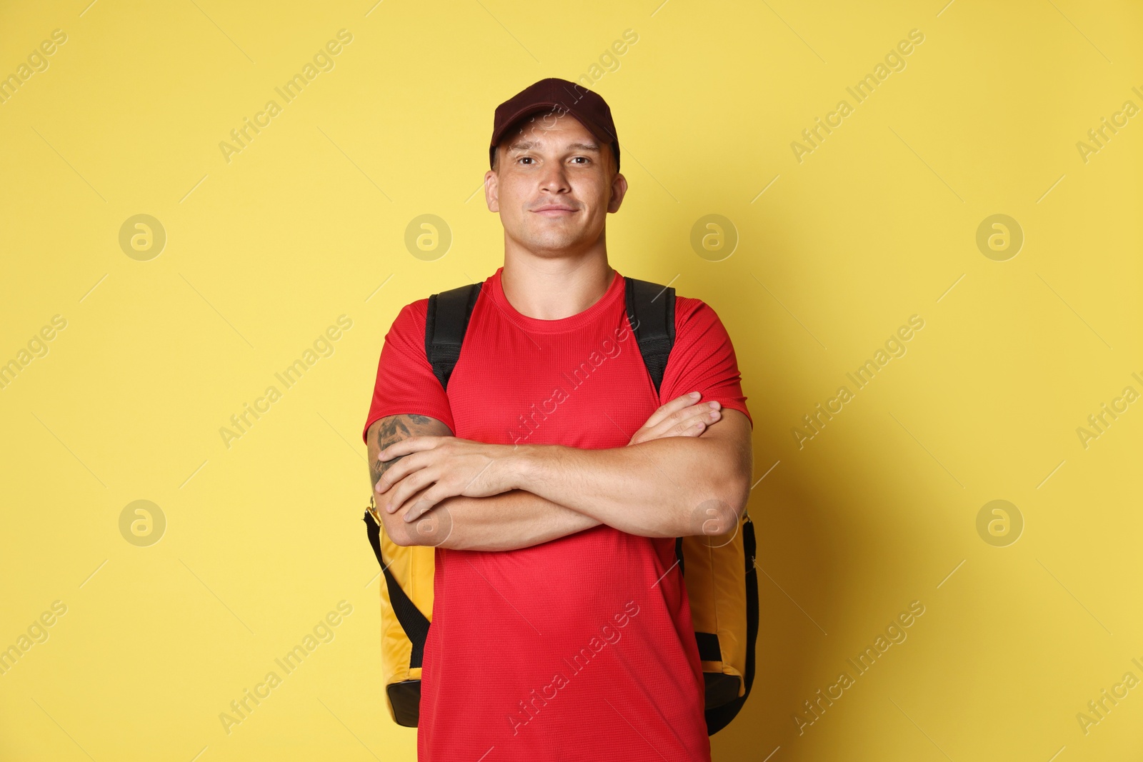 Courier with thermo bag on yellow background. Food delivery service Photo of Courier with thermo bag on yellow background. Food delivery service
