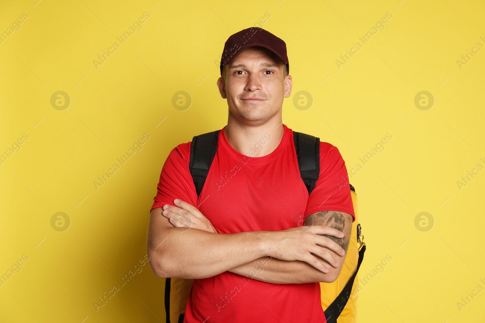 Courier with thermo bag on yellow background. Food delivery service Photo of Courier with thermo bag on yellow background. Food delivery service