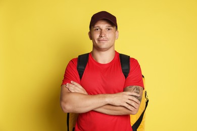 Photo of Courier with thermo bag on yellow background. Food delivery service