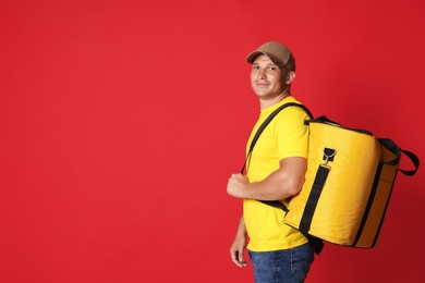 Photo of Courier with thermo bag on red background, space for text. Food delivery service