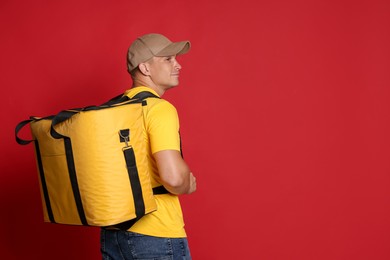 Photo of Courier with thermo bag on red background, space for text. Food delivery service