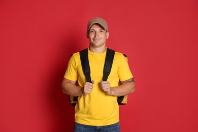 Photo of Courier with thermo bag on red background. Food delivery service