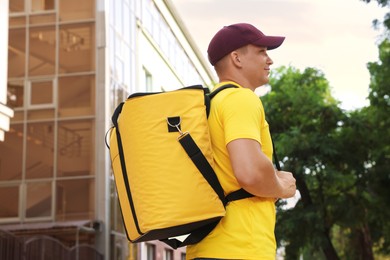 Photo of Courier with thermo bag on city street, low angle view. Food delivery service