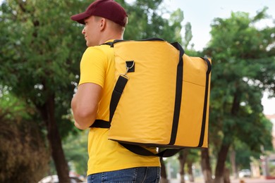 Photo of Courier with thermo bag on city street, low angle view. Food delivery service