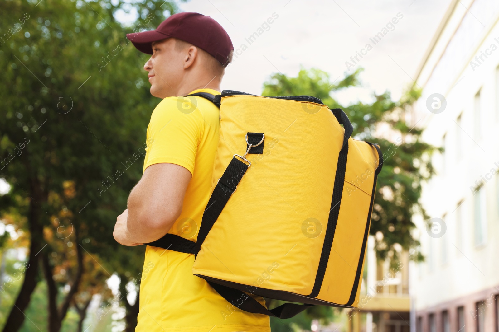 Courier with thermo bag on city street, low angle view. Food delivery service Photo of Courier with thermo bag on city street, low angle view. Food delivery service