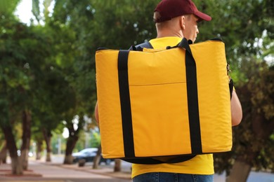Photo of Courier with thermo bag on city street, back view. Food delivery service