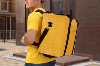 Photo of Courier with thermo bag on city street, closeup. Food delivery service