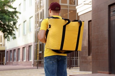 Photo of Courier with thermo bag on city street, back view. Food delivery service