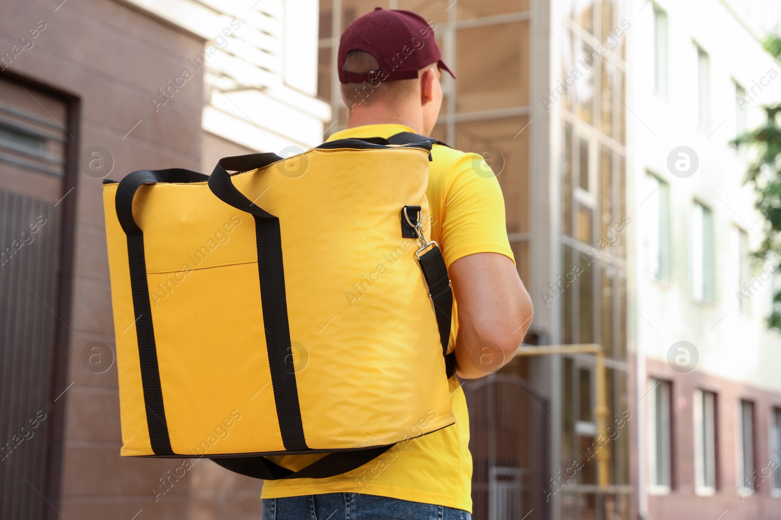 Courier with thermo bag on city street, back view. Food delivery service Photo of Courier with thermo bag on city street, back view. Food delivery service