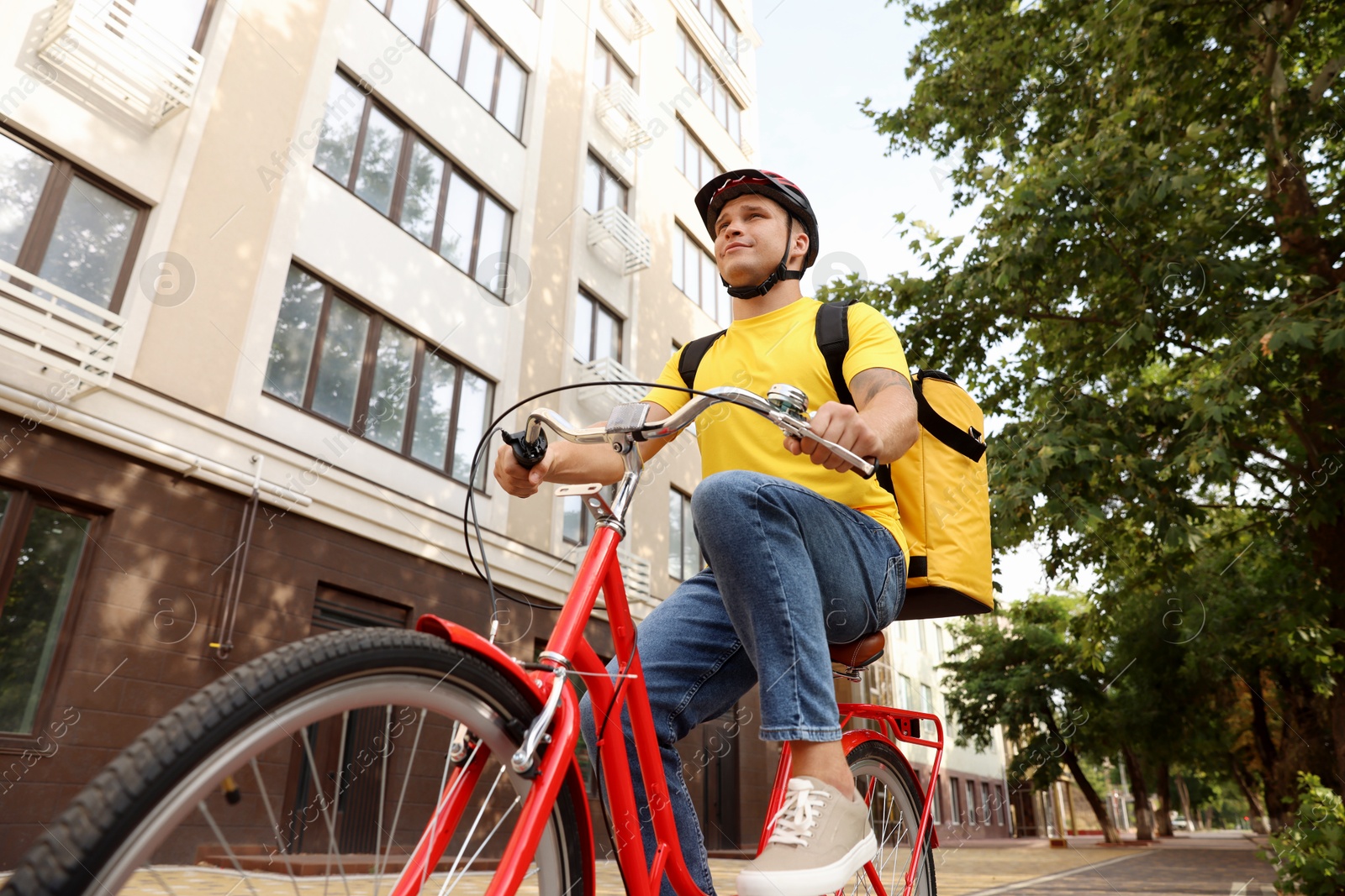 Courier with thermo bag riding bicycle outdoors, low angle view. Food delivery service Photo of Courier with thermo bag riding bicycle outdoors, low angle view. Food delivery service